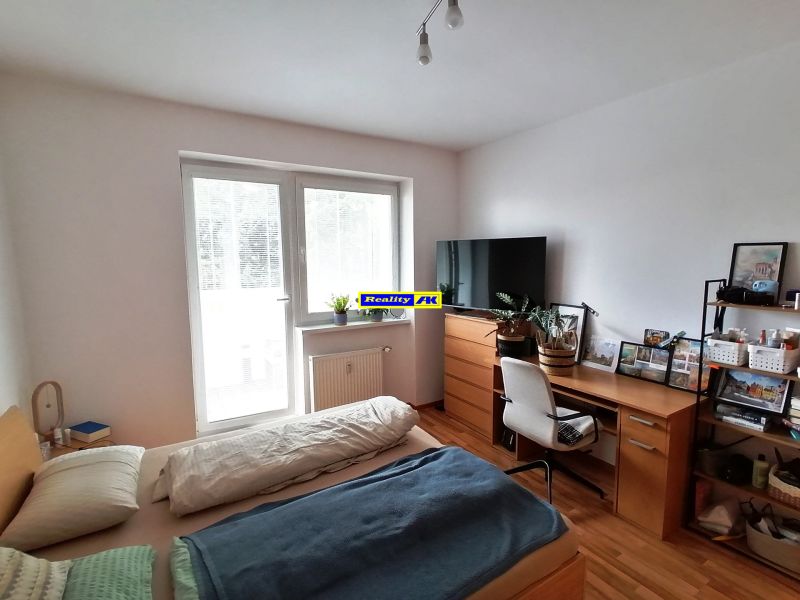 1 izbový byt na predaj rekonštrukcia, Martin centrum, nový balkón - Spálňová zóna v 1-izbovom byte s podlahou s dreveným dekorom a pracovným stolom.