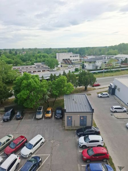 Iba u nás prenajom zariadeneho 1izb bytu - Parkovisko s autami, zeleňou a budovami v Nových Zámkoch na ulici Nábrežná.