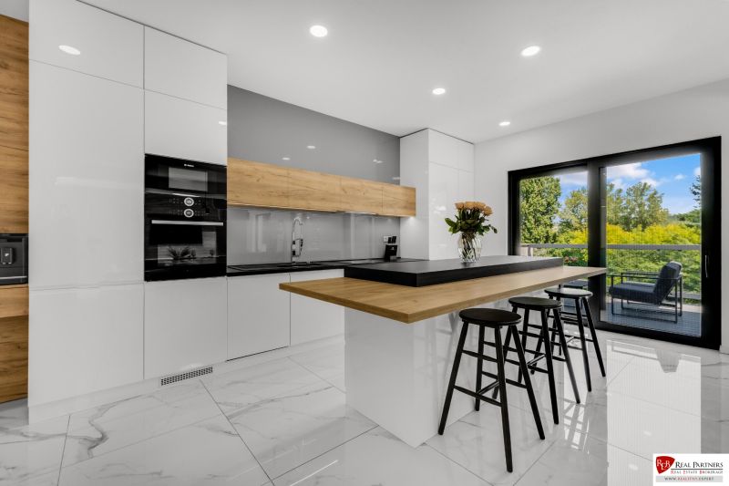 Na predaj nádherný 4 izbový luxusný byt,176 m2 + terasy 55 m2,2 garáž. - Kuchyňa v 4-izbovom byte s podlahou s dreveným dekorom a veľkými presklenými dverami.