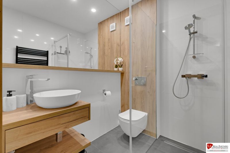 Na predaj nádherný 4 izbový luxusný byt,176 m2 + terasy 55 m2,2 garáž. - Kúpeľňa 4-izbového bytu s podlahou s dreveným dekorom a sprchovým kútom.