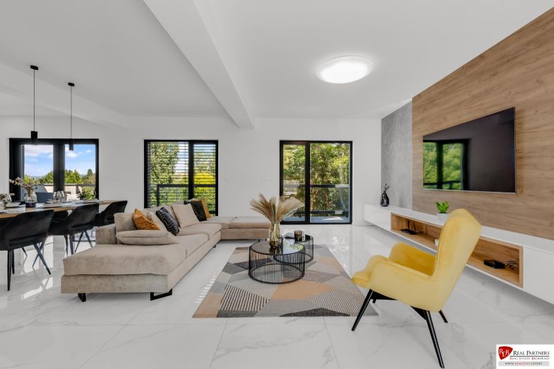 Na predaj nádherný 4 izbový luxusný byt,176 m2 + terasy 55 m2,2 garáž. - Otvárajúca obývacia izba s pohodlnou sedačkou, žltým kreslom a TV na stene.