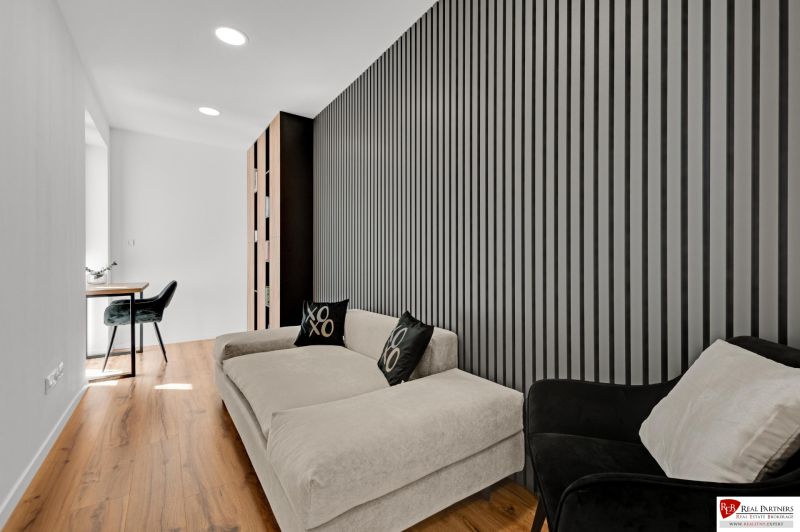 Na predaj nádherný 4 izbový luxusný byt,176 m2 + terasy 55 m2,2 garáž. - Moderný interiér s pohovkou, kreslom, pracovným stolom a vertikálnou stenou v 4-izbovom byte.