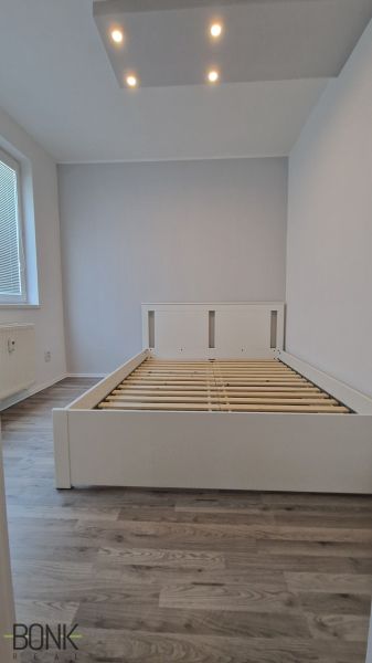 Predaj útulný, úplne prerobený 2 izbový byt s loggiou, Rajecká ulica. - Manželská posteľ v izbe s podlahou s dreveným dekorom a stropným osvetlením.