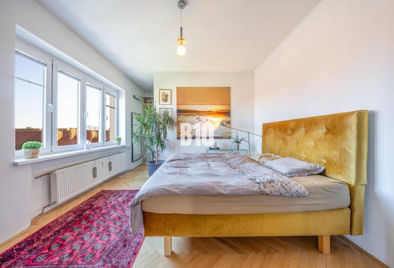Prenájom | 2-izbový byt | Záhradnícka – Poľská ulica | 900 € + 200 € e - Svetlá spálňa s posteľou a podlahou s dreveným dekorom v 2-izbovom byte.