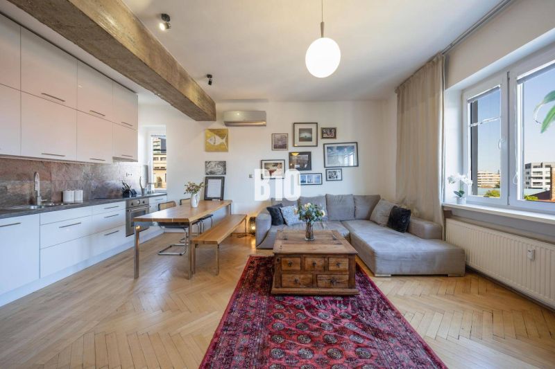 Prenájom | 2-izbový byt | Záhradnícka – Poľská ulica | 900 € + 200 € e - Obývačka s kuchyňou v 2-izbovom byte, podlaha s dreveným dekorom, sedačka, jedálenský stôl.