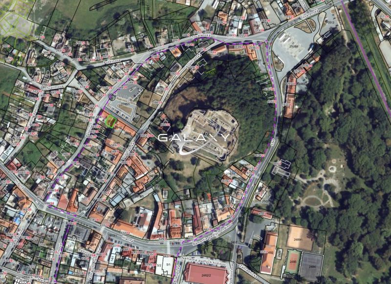 Pozemok v tesnej blízkosti hradu – Fiľakovo - Letecký pohľad na pozemky v historickom centre Fiľakova, obklopené budovami a zeleňou.