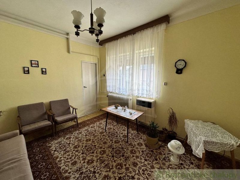 Rodinný dom na veľkom pozemku pri mŕtvom ramene Malého Dunaja v Koláro - Obývacia izba v rodinnom dome s kobercom a záclonami. Retro nábytok dopĺňa útulnú atmosféru.