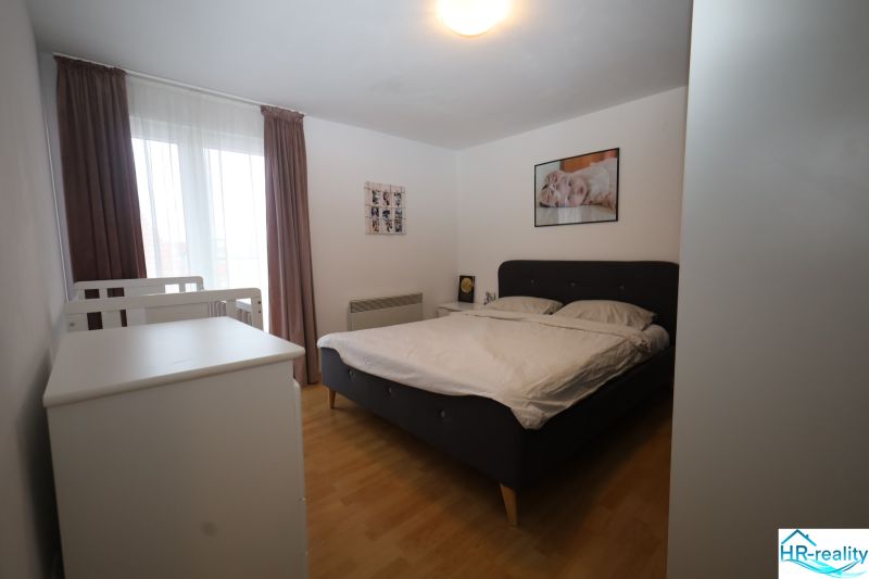Vodice(HR)-Kompletne zariadený 3 izbový apartmán - Spálňa s posteľou a detskou postieľkou v Rekreačnom apartmáne, podlaha s dreveným dekorom.