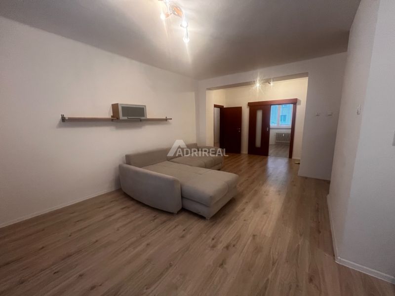 PREDAJ: 3i s balk. 67 m2; Uhlisko-Banská Bystrica; 205.000 € - Obývacia izba s pohovkou a podlahou s dreveným dekorom v 3-izbovom byte.