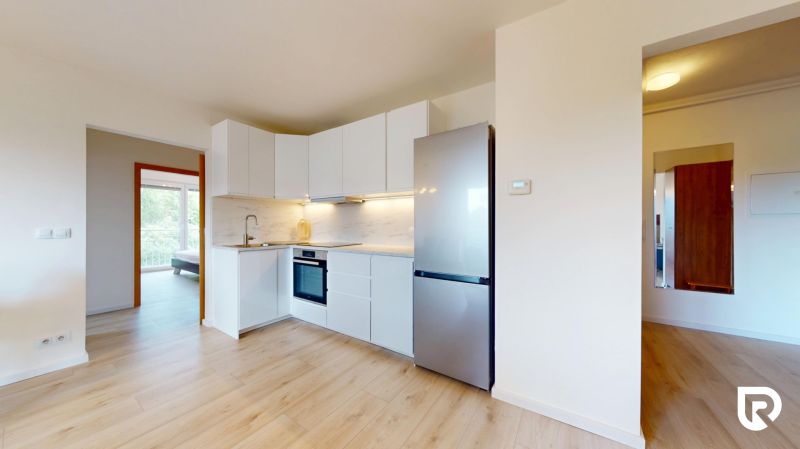 | Pekný a priestranný 3-izbový byt | 70m² |  - Kuchyňa s bielou linkou, vstavanými spotrebičmi a podlahou s dreveným dekorom v 3-izbovom byte.