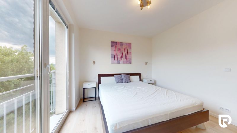 | Pekný a priestranný 3-izbový byt | 70m² |  - Svetlá spálňa s podlahou s dreveným dekorom, posteľou a balkónovými dverami v 3-izbovom byte.
