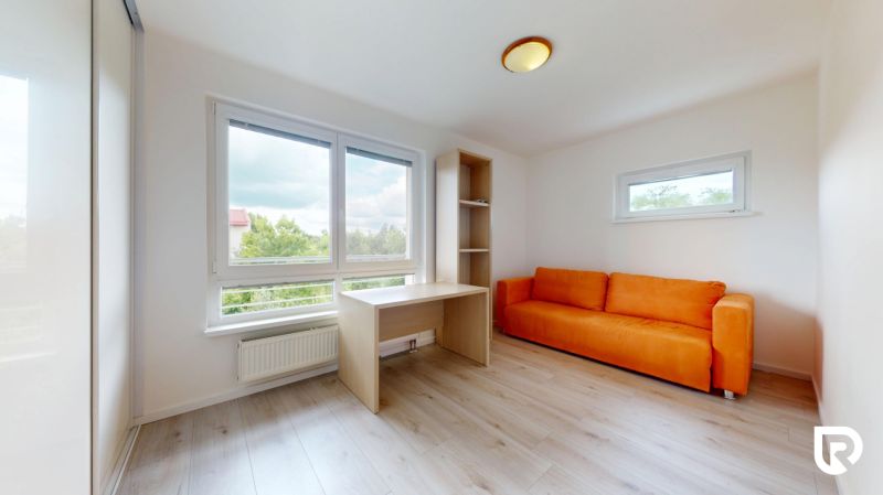 | Pekný a priestranný 3-izbový byt | 70m² |  - Izba v 3-izbovom byte s oranžovou pohovkou, stolom a podlahou s dreveným dekorom.