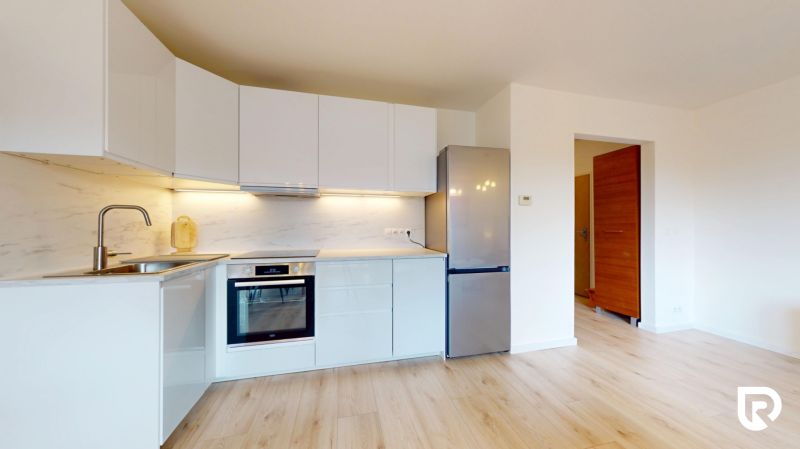 | Pekný a priestranný 3-izbový byt | 70m² |  - Kuchyňa v 3-izbovom byte s bielymi skrinkami a podlahou s dreveným dekorom.