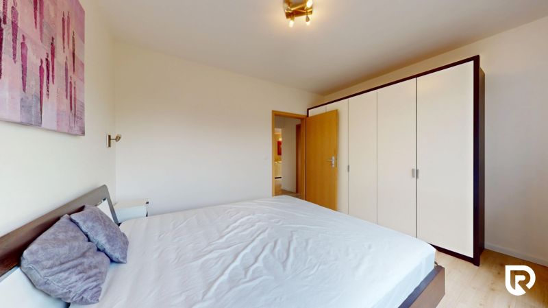 | Pekný a priestranný 3-izbový byt | 70m² |  - Spálňa s veľkou šatníkovou skriňou, posteľou a umením v 3-izbovom byte.