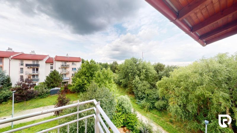 | Pekný a priestranný 3-izbový byt | 70m² |  - Výhľad z balkóna na Mečíkovej ulici v Devínskej Novej Vsi s bohatou zeleňou.