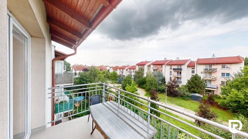 | Pekný a priestranný 3-izbový byt | 70m² |  - Balkón z 3-izbového bytu s výhľadom na zeleň a okolité budovy v Devínskej Novej Vsi.