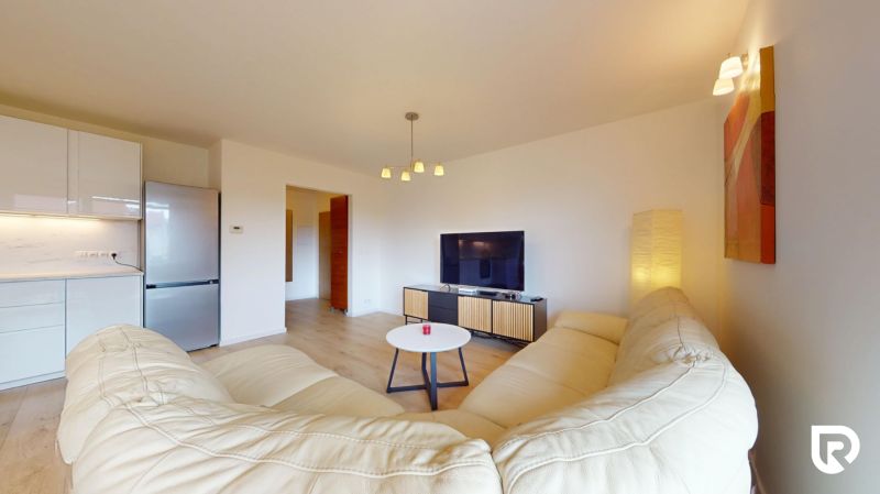 | Pekný a priestranný 3-izbový byt | 70m² |  - Obývacia izba v 3-izbovom byte s gaučom, televíziou a podlahou s dreveným dekorom.