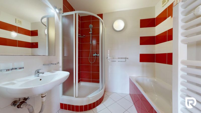 | Pekný a priestranný 3-izbový byt | 70m² |  - Kúpeľňa v 3-izbovom byte s vaňou, sprchovacím kútom a červenými obkladmi.