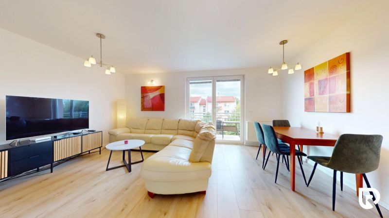 | Pekný a priestranný 3-izbový byt | 70m² |  - Obývačka v 3-izbovom byte s podlahou s dreveným dekorom, sedačkou a jedálenským stolom.