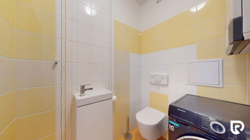 | Pekný a priestranný 3-izbový byt | 70m² |  - Kúpeľňa s práčkou v 3-izbovom byte, kombinácia bielych a žltých obkladov.
