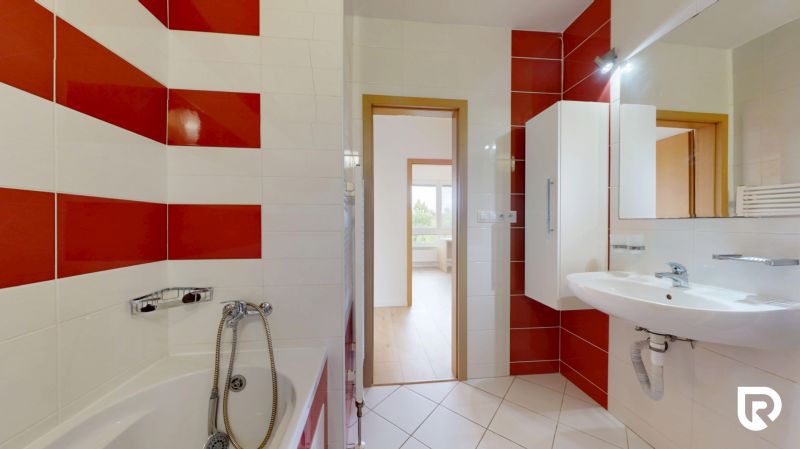 | Pekný a priestranný 3-izbový byt | 70m² |  - Kúpeľňa v 3-izbovom byte s bielymi a červenými kachličkami, umývadlom a vaňou.