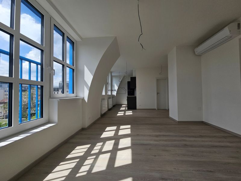 VÝNIMOČNÝ SLNEČNÝ APARTMÁN v centre mesta, UNO Poštová - Priestranná miestnosť s veľkými oknami, podlaha s dreveným dekorom v 1-izbovom byte.