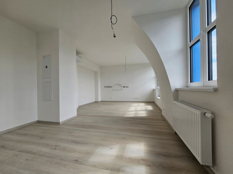 VÝNIMOČNÝ SLNEČNÝ APARTMÁN v centre mesta, UNO Poštová - Priestranná obývačka s podlahou s dreveným dekorom a veľkými oknami v 1-izbovom byte.