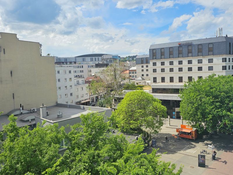 VÝNIMOČNÝ SLNEČNÝ APARTMÁN v centre mesta, UNO Poštová - Výhľad na Poštovú ulicu v Bratislave - Starom Meste so zeleňou a budovami.