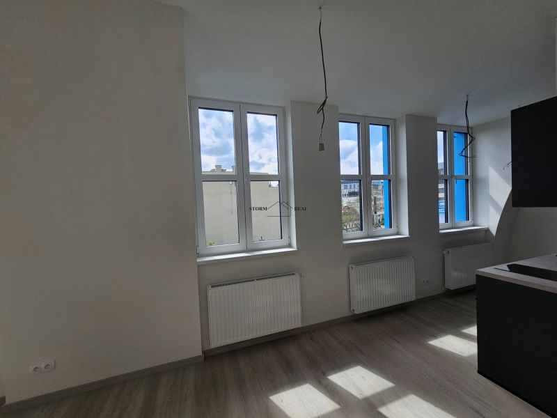 VÝNIMOČNÝ SLNEČNÝ APARTMÁN v centre mesta, UNO Poštová - Svietlá miestnosť s tromi oknami a podlahou s dreveným dekorom v 1-izbovom byte.