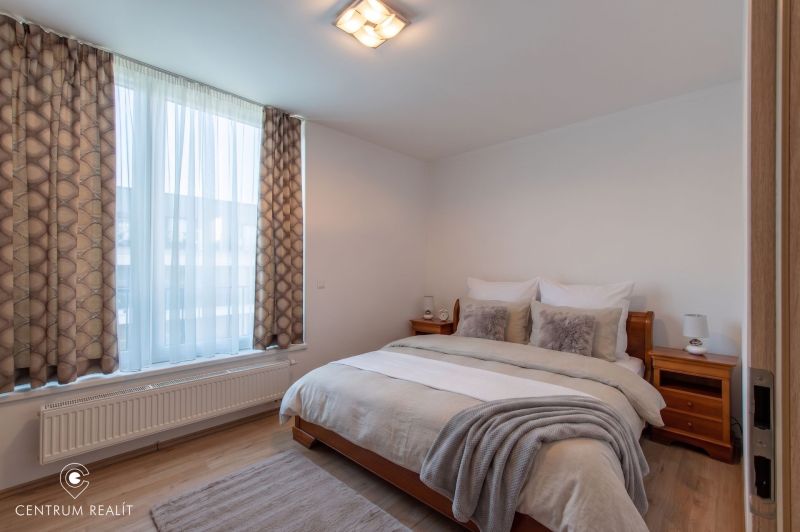 Moderný 2-izbový apartmán s parkovaním, Vila Leonardo, Bajkalská - Spálňa s veľkým oknom, dvojlôžkom a podlahou s dreveným dekorom v 2-izbovom byte.