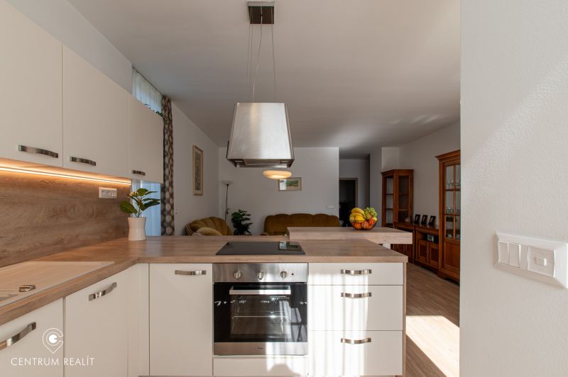 Moderný 2-izbový apartmán s parkovaním, Vila Leonardo, Bajkalská - Kuchyňa v 2-izbovom byte s podlahou s dreveným dekorom a bielymi skrinkami.