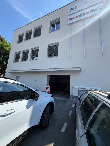 Ponúkame na prenájom 2 garáž / priestor v blízkosti centra Prievidze - Budova s garážami na dlhej ulici 3 v Prievidzi, zaparkované autá pred budovou.