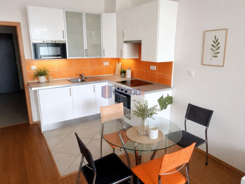 Garsonka 35m2, balkón,novostavba, Sliačska ul. Energie v cene. - Kuchyňa v garsónke s bielou linkou, oranžovým obkladom a okrúhlym stolom s dreveným dekorom.