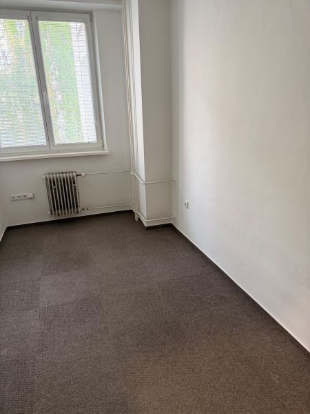 Ponúkame najlacnejšie  kancelárske priestory v Prievidzi  - Kancelária s kobercom, radiátorom a oknom so žalúziami.
