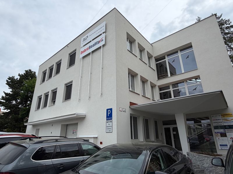 Ponúkame najlacnejšie  kancelárske priestory v Prievidzi  - Budova kancelárií na Dlhej ulici v Prievidzi so zaparkovanými autami.