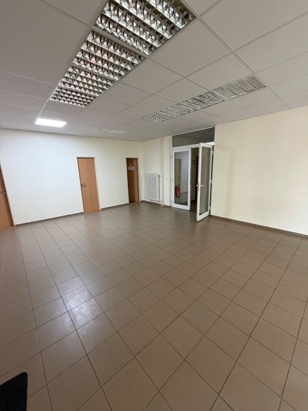 Ponúkame na prenájom priestrannú kanceláriu vPrievidzi - Prázdne kancelárie s dlaždicovou podlahou a bielymi stenami.