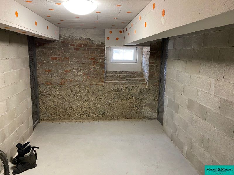 Byt na rekonštrukciu v centre Bratislavy – výborný projekt - Pivničná miestnosť s betónovými stenami a oknom v 2-izbovom byte.
