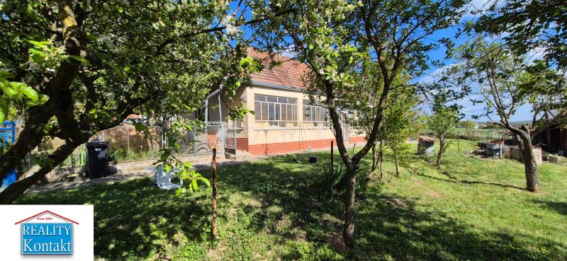Na predaj vidiecky dom v Dedinke 3+1 s pozemkom 3150m2  - Rodinný dom v Dedinke obklopený záhradou s ovocnými stromami, modrá obloha.