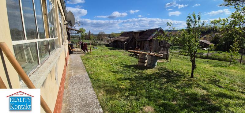 Na predaj vidiecky dom v Dedinke 3+1 s pozemkom 3150m2  - Rodinný dom v Dedinke s veľkou záhradou, zeleňou a staršou budovou v pozadí.