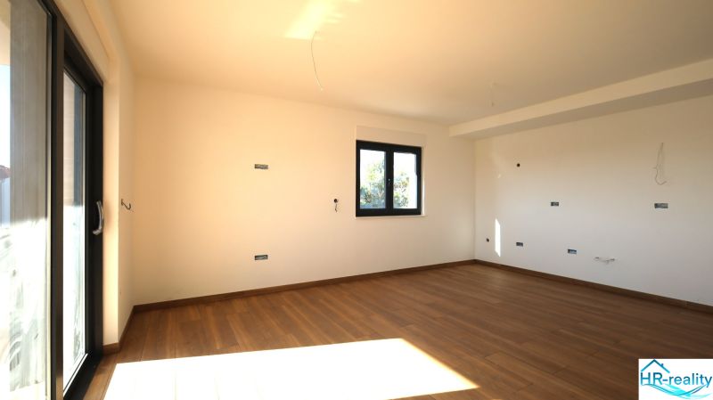 Vodice(HR)-3-izbový byt 81 m2 so záhradou - Priestranná miestnosť s veľkým oknom a podlahou s dreveným dekorom v Rekreačnom apartmáne.