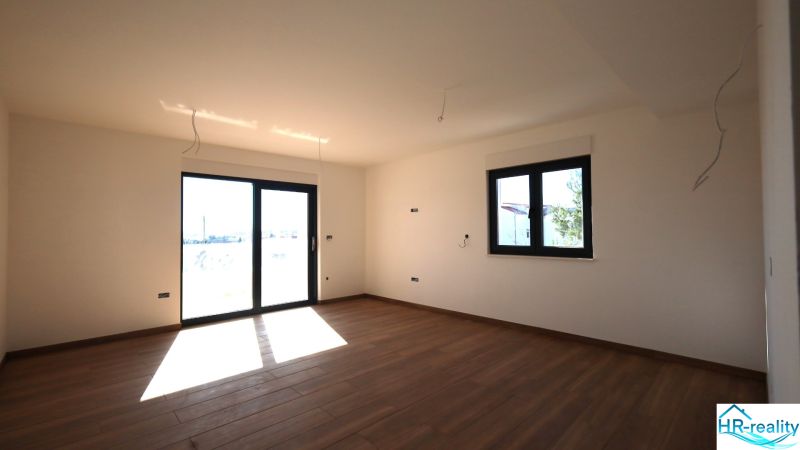 Vodice(HR)-3-izbový byt 81 m2 so záhradou - Interiér rekreačného apartmánu s veľkými oknami a podlahou s dreveným dekorom.