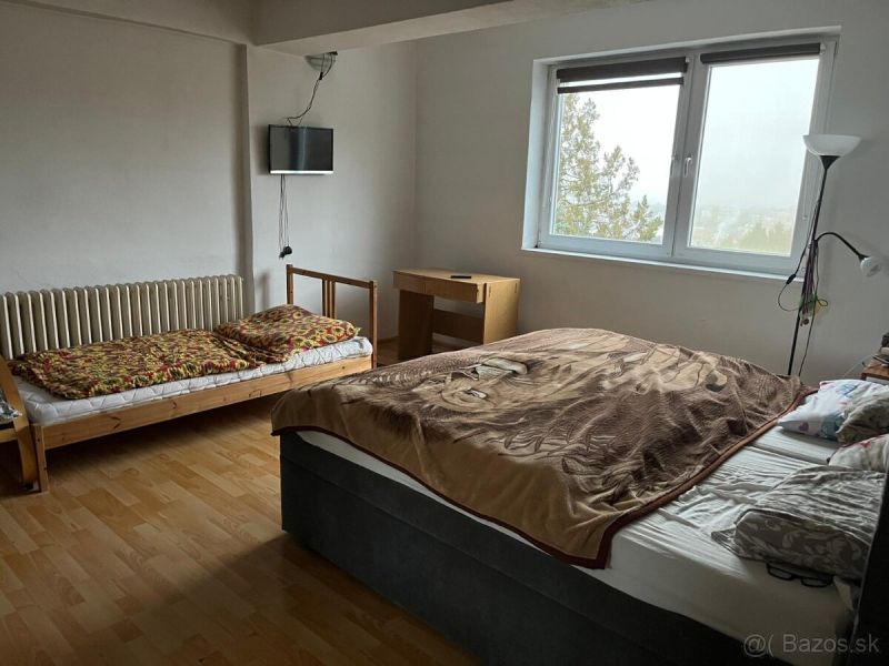 Rodinný dom v Štitároch s výhľadom a pod lesom - Spálňa v rodinnom dome s posteľou, lôžkom, stolom, oknom a podlahou s dreveným dekorom.