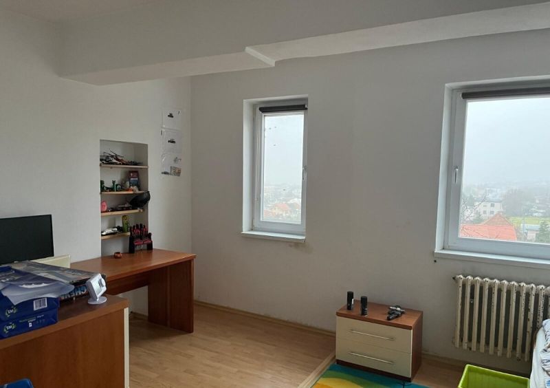 Rodinný dom v Štitároch s výhľadom a pod lesom - Izba v rodinnom dome s písacím stolom, policami, radiátorom a podlahou s dreveným dekorom.