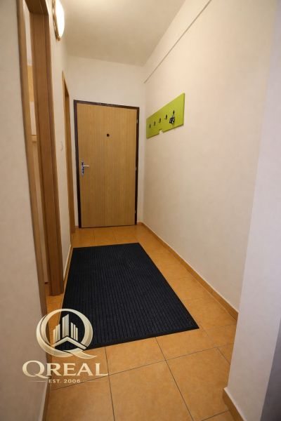*BEZ PROVÍZIE**Bývanie na ZAČIATKU Petržalky, zariadenie, klimatizácia - Úzka chodba v 3-izbovom byte s dláždenou podlahou a zeleným vešiakom.