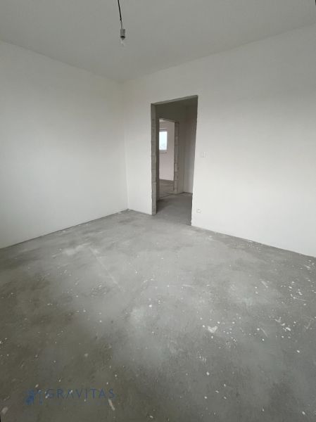 Na predaj 3 izb. byt s balkónom blízko centra - Prázdna miestnosť v 3-izbovom byte s betónovou podlahou a nedokončenými stenami.