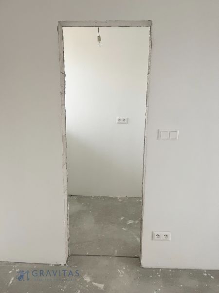 Na predaj 3 izb. byt s balkónom blízko centra - Neomietnuté dvere v 3-izbovom byte zobrazujú surovú podlahu a biele steny.