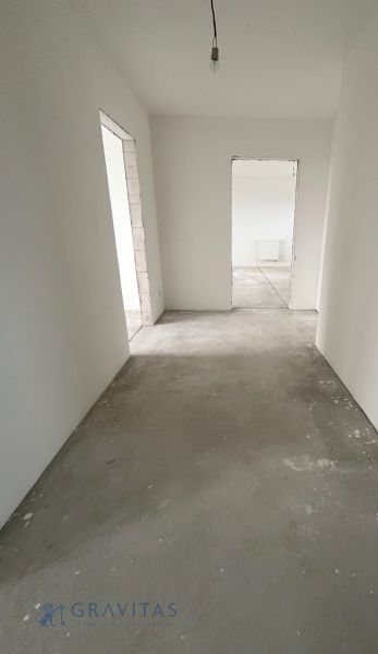 Na predaj 3 izb. byt s balkónom blízko centra - Chodba v 3-izbovom byte s betónovou podlahou a bielymi stenami.