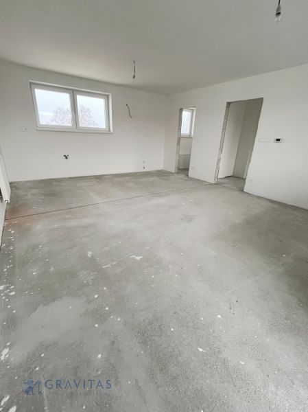 Na predaj 3 izb. byt s balkónom blízko centra - Prázdna miestnosť v 3-izbovom byte bez podlahovej krytiny a s bielymi stenami.