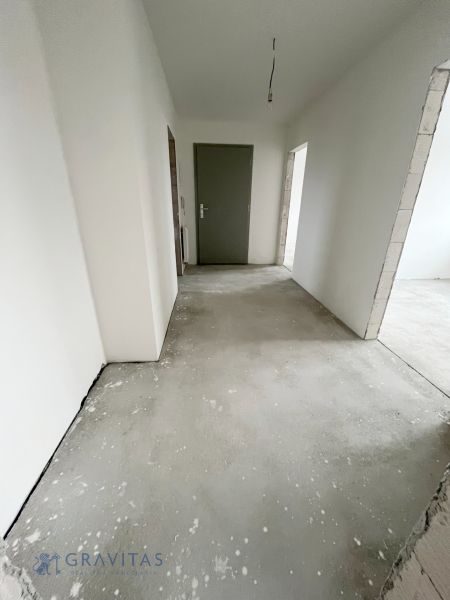 Na predaj 3 izb. byt s balkónom blízko centra - Chodba v 3-izbovom byte so sivými dverami a neukončenou podlahou.