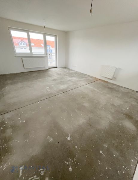 Na predaj 3 izb. byt s balkónom blízko centra - Prázdna miestnosť v 3-izbovom byte so základnou podlahou a bielymi stenami.